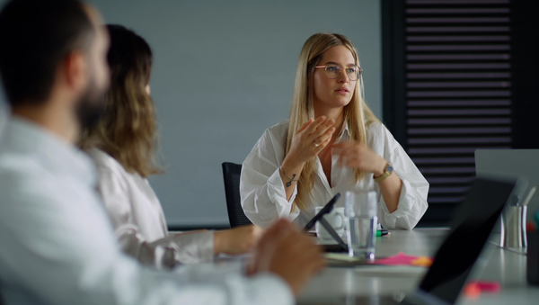 Eine Mitarbeiterin tauscht sich in einem Meeting mit Mitarbeitenden aus.
