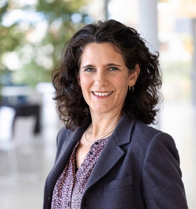 Frau Dreher steht Portrait und lächelt in die Kamera.