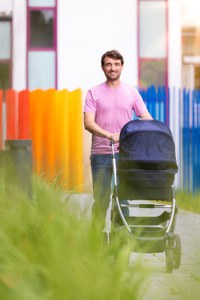 Ein Mitarbeiter schiebt im Freien einen Kinderwagen über das Campus-Gelände.